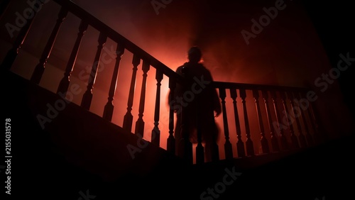 Fototapeta kuchenna Silhouette of a mysterious figure standing on a dark staircase in a spooky house