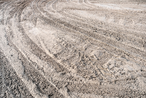 Rough ground soil texture background with wheel tracks