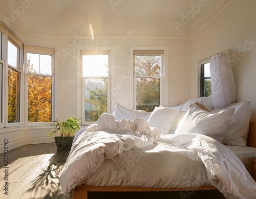 sunlit pristine white bed with piled pillows and rumpled sheets evoking a feeling of calm