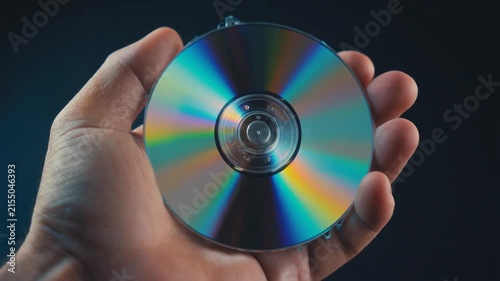 Hand holding a shiny metallic computer disk representing digital data storage technology