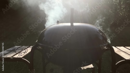 Backlit smoke rising from closed grill at sunset