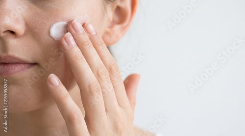 Close-up shot of a woman applying cream to her face, showcasing a skincare routine