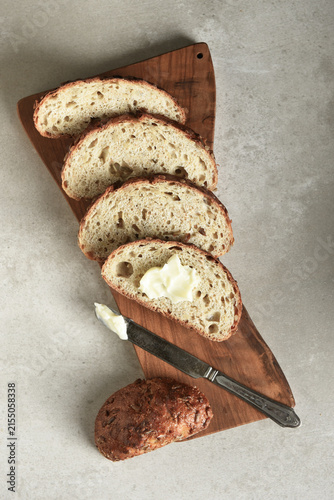 Bread Still Life. Fresh baked lices of a multi grain loaf of bread arranged on a cutting board with a knife and butter.