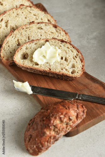 Bread Still Life. Fresh baked lices of a multi grain loaf of bread arranged on a cutting board with a knife and butter.