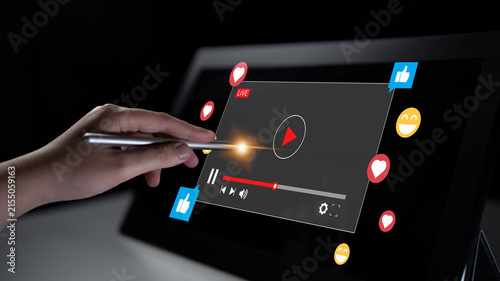 Obraz na plátne A hand engages with a digital screen showcasing a live streaming interface, highlighting modern technology and viewer reactions in a creative, dark setting