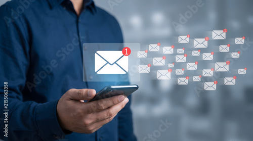 Businessman using a smartphone to manage a high volume of digital email notifications and incoming messages in a modern corporate office