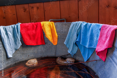 Colorful reusable microfiber cleaning cloths and towels draped over the rim of a galvanized metal tub