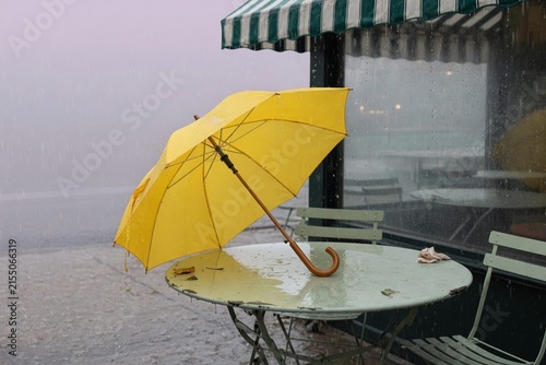 Yellow umbrella leaning cafe table empty