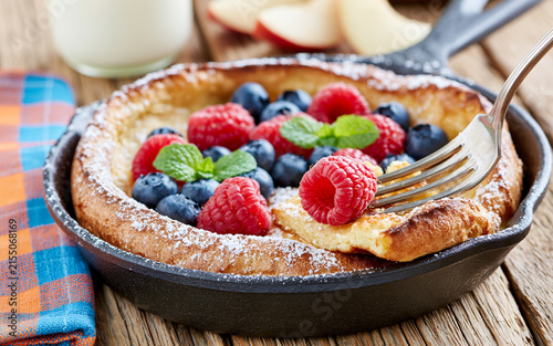 Dutch baby pancake with apples and cinnamon in a pan on a table close-up