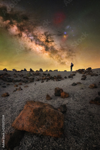View of a person standing on the volcanic terrain of Minas de San Jose under the bright Milky Way galaxy at night in La Orotava, Canary Islands, Spain.