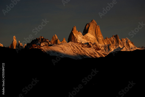 Famous Mount Fitz Roy glowing at sunset above snowy peaks in El Chaltén, Patagonia, Argentina.
