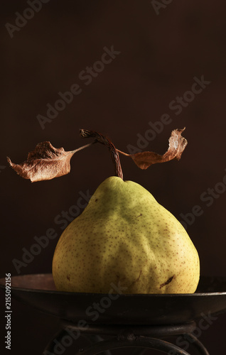 Fruit Still Life. An Anjou Pear on a pedestal against a warm brown mottled background.