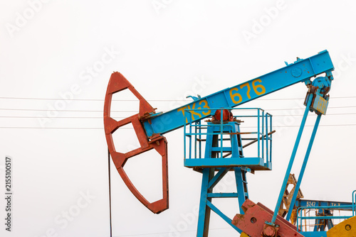 View of a blue industrial oil pumpjack with a red counterweight operating in an oil field in Zhanaozen, Mangystau Region, Kazakhstan.
