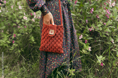 Woman in floral dress holding handmade terracotta crochet shoulder bag