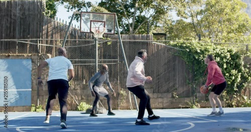 Diverse men on court passing ball red hoodie shooting for basket gray leaper blocking reacting