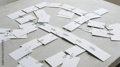 White blank cards connected with colorful paper clips on concrete