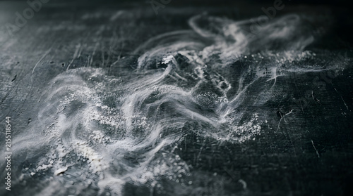 White flour scattered on dark surface with swirl patterns