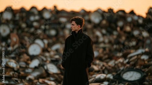 Time Passing Concept with Man Standing Before Pile of Old Clocks at Sunset
