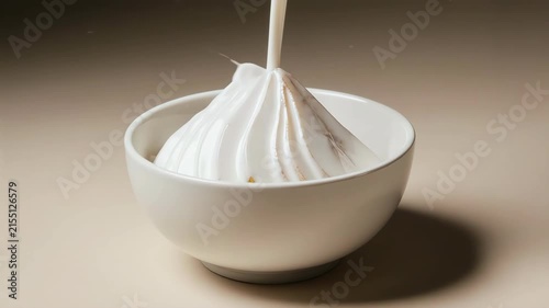 Thin pear slices arranged inside white ceramic bowl, fresh cream cascading slowly from above in ultra slow motion