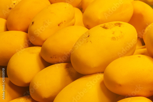 Full frame view of ripe, golden yellow Nam Dok Mai mangoes tightly arranged on a market display