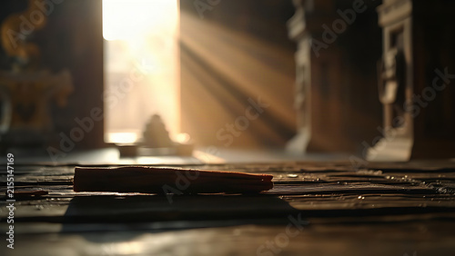 A piece of frankincense resin on dark wood in warm, dusty sunlight.