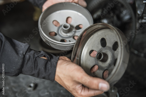 Mechanic hands holding motorcycle clutch bells for inspection during CVT transmission repair
