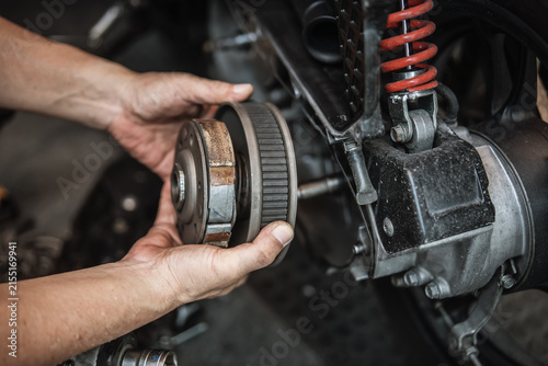 technician installing the outer clutch drum on a scooter engine. This image shows the professional assembly process of the motorcycle's centrifugal clutch and transmission system.