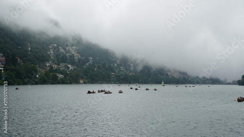 Photography Boats on Nainital Lake with misty hills and colorful houses, overcast day during
