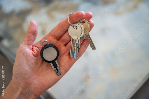 Hands holding traditional metal keys and an RFID key fob together. Concept of transition from mechanical locks to electronic access control and smart security technology