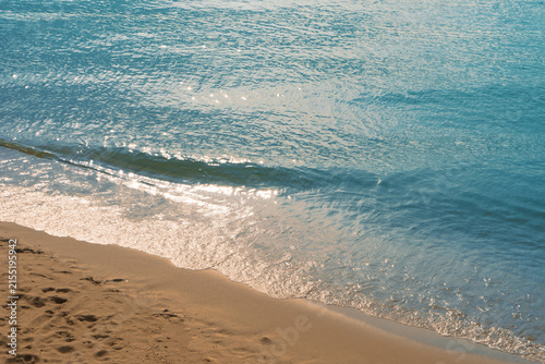 Foto Tranquil blue sea water and golden sand beach with sunlight reflection at Rayong