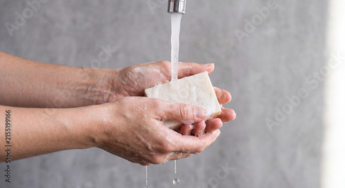 Close up shot of hands washing with organic bar soap under clean running tap water.