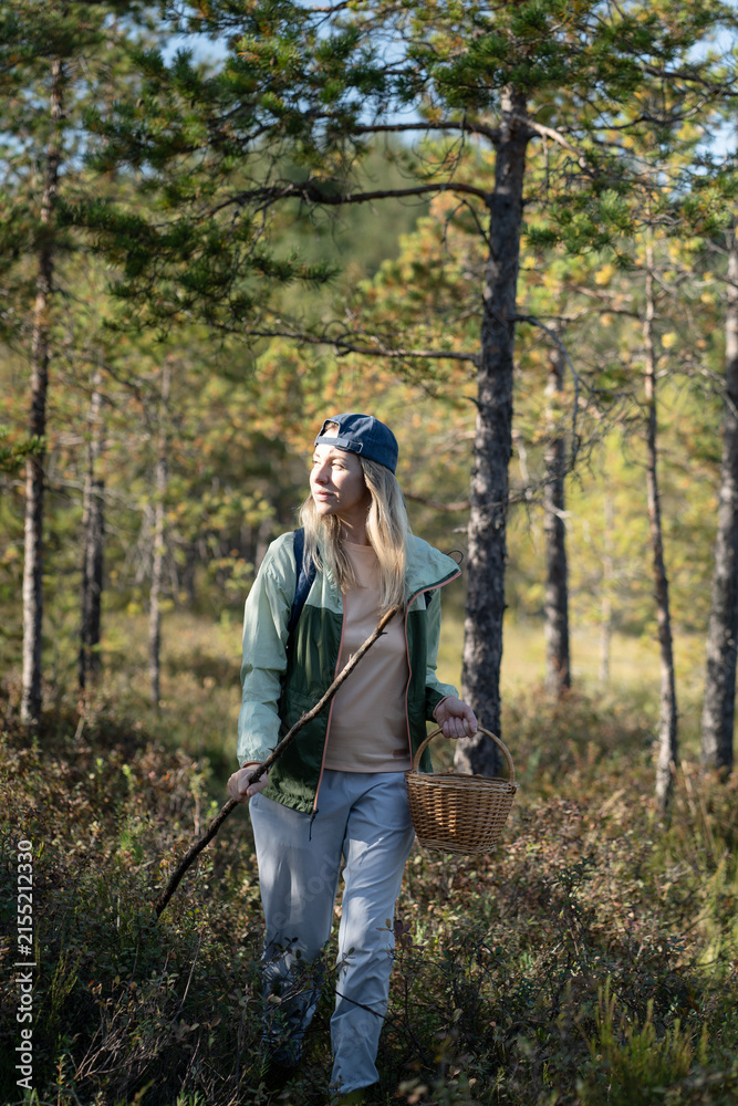 Obraz premium Mature woman strolling through forest, physical activity outdoors and healthy living, female solo hiking in woodlands, walking making way on trekking path in thickets, getaway in nature.
