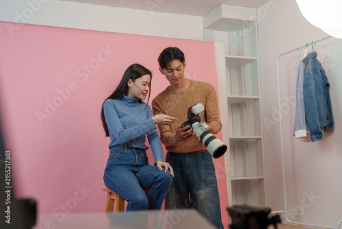 Cuadro en lienzo Asian photographer showing preview photos on camera display to female model