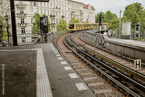 Berlin, Germany - 05 June 2026: View of the yellow U-Bahn train traveling along the elevated tracks in Berlin, with historic buildings and green trees in the background.
