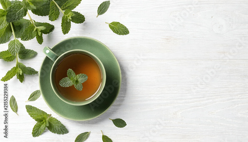 Fresh Mint Tea with Green Cup and Leaves on White Wooden Table