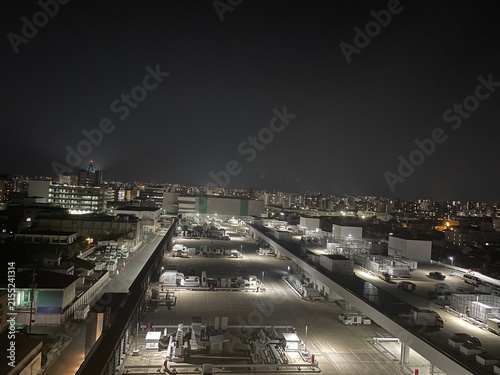 Naklejka 照明に照らされた夜間の広大な屋上駐車場と輝く街の明かり