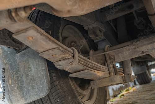 Fotografía Close up undercarriage view of a rusty car leaf spring suspension system and wheel, highlighting classic vehicle maintenance, heavy-duty suspension repair, and automotive care
