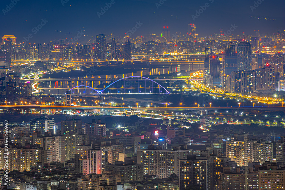 Fototapeta premium Illuminated bridges and dense Taipei skyline across the river at night