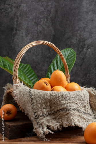 Fresh Loquat Fruits in Rustic Basket with Green Leaves
