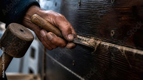 Boat Caulker Uses Mallet and Chisel to Repair Wooden Hull with Oakum