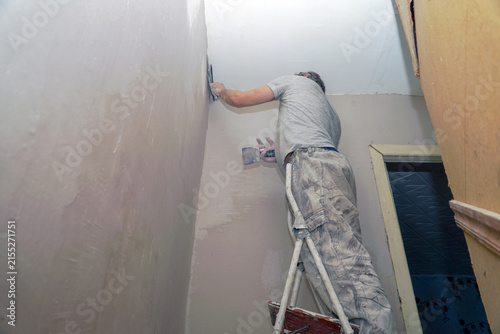 A man plastering a wall with a spatula
