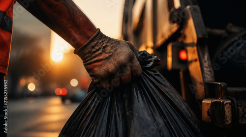 Refuse Collectors Dirty Gloved Hand Holding Black Garbage Bag at Sunset