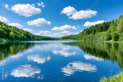 Clear lake reflecting blue sky and green forest