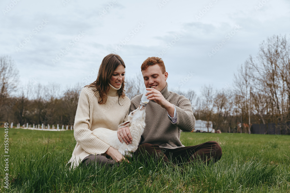 Obraz premium couple outdoors lifestyle dog meadow grass sweater happiness relaxed candid nature joyful affection companionship sunlight greenery field scenery moment bonding warmth park breeze comfort casual