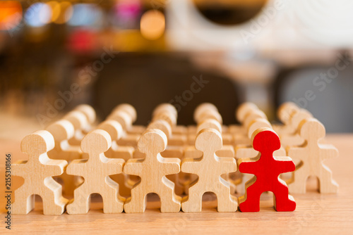 Obraz na plátně Unique red wooden figure standing out among natural wood people figures row, concept for leadership, uniqueness, individuality, recruitment, stand out, candidate, and distinction