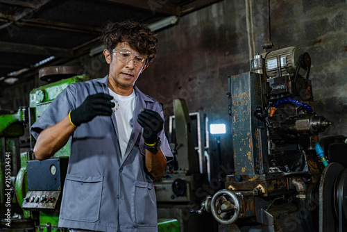 Fotografie Asian father with curly hair inside his old family machine shop, dad squares to