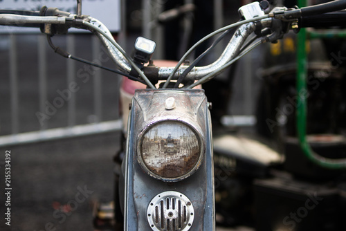 Front view of vintage motor scooter with round headlight chrome handlebar and horn grill