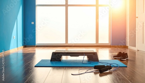 Fitness equipment with aerobic step platform, jump rope, and sneakers in a bright sunlit home gym