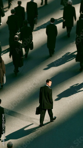 People walk on a busy street during the day while one man looks back at the camera
