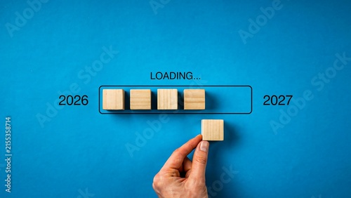 Hand placing a loading block between 2026 and 2027 to represent progress and future transition